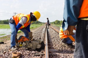 Workers cutting ballast near railroad ties for railroad maintenance
