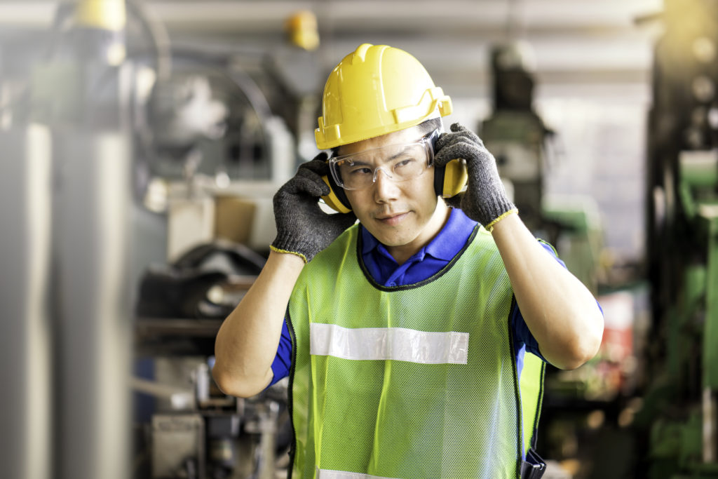 Professional technicians wear protective equipment and hard hats in large industrial plants. Protective and Safety Equipment eye wear, ear plug, vis clothes and protective helmet.